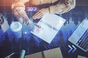Forex graph on hand taking notes background. Concept of research. Double exposure