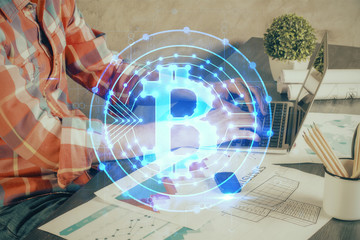 Crypto currency theme hologram with businessman working on computer on background. Concept of blockchain. Multi exposure.