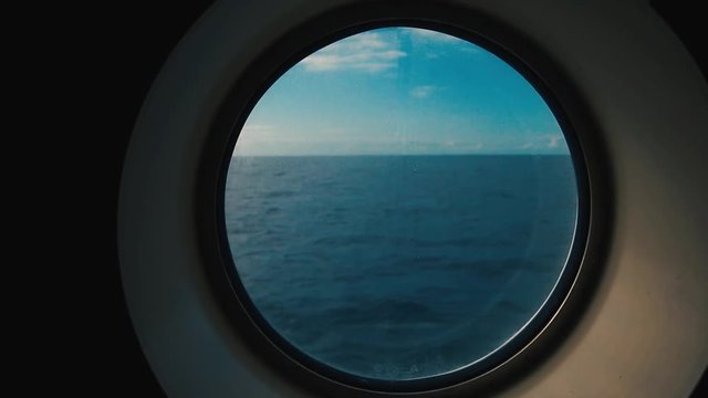 The view from weather sealed round porthole window onboard a vessel ship navigating through the ocean sea. Blue sky with clouds, adventurer, exploring, discover
pin
