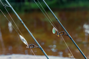 two spinning and catching bait for catching predatory fish on the background of the pond, selective...