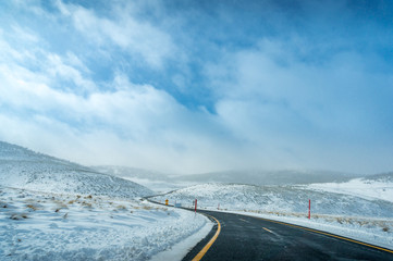 Winter landscape with ice covered bending asphalt road