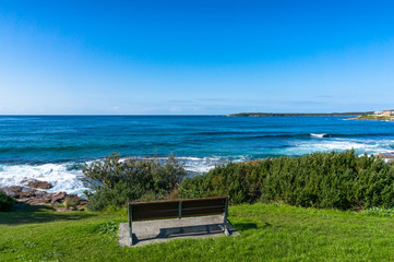 Naklejka na ściany i meble Ocean landscape with one bench on a cliff