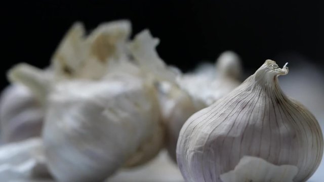 Whole garlic bulbs and garlic skin is blown away in slow motion