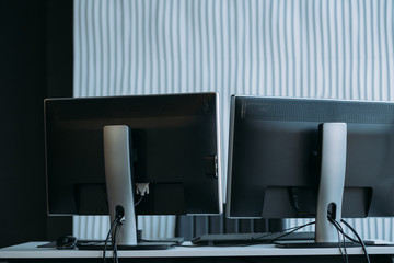 Software developer workplace. Two monitors on office desk. Textured wall background. Copy space.