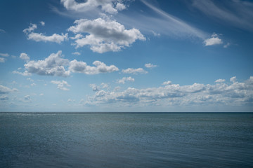 white clouds float in the sky above the sea