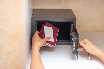 Hand opening safe in the hotel room, putting passport and credit cart