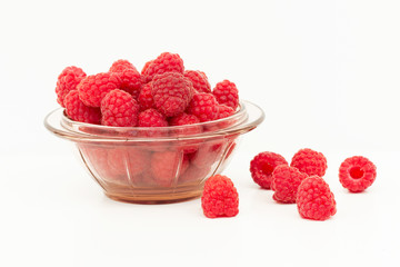 Fresh ripe raspberries on a white background in a glass jar and scattering