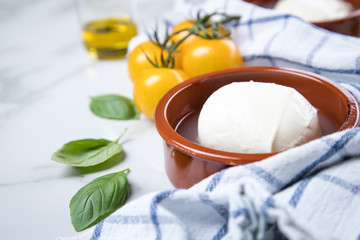 Gelbe Tomaten mit Mozzarella, Basilikum und Olivenöl auf Marmor Hintergrund und Geschirrtuch