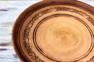 Empty clay handmade plate (dish) with a traditional Ukrainian pattern on old white wooden background