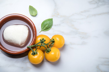 Gelbe Tomaten mit Mozzarella und Basilikum auf Marmor Hintergrund 