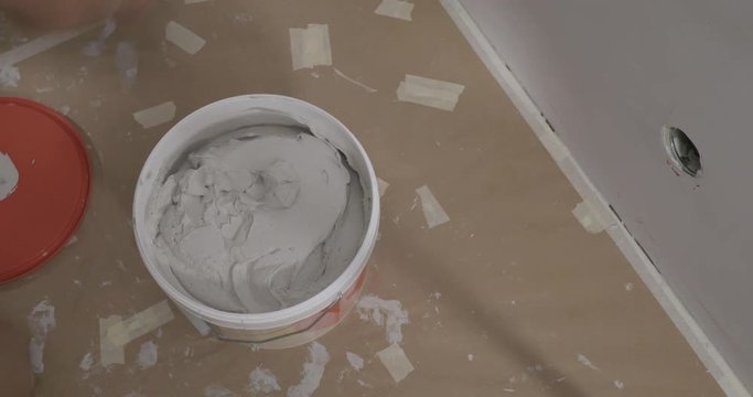 Norwegian adult opens a bucket of spackle for his refurbishment project.