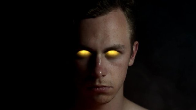 Ancient Greek like god being with yellow golden glowing eyes and smoke around him looking into camera.