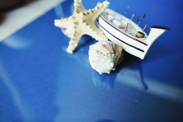 White little toy ship with shells on a blue background