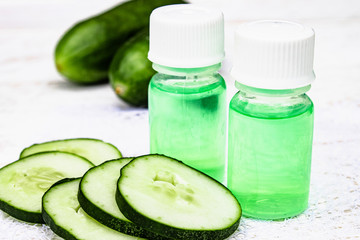 Sliced cucumber and a bottle of cucumber extract. Liquid cosmetics for skin care.
