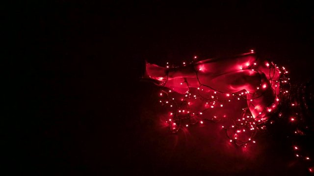 Wide shot of sexy female legs on the ground in a dark room tangled in red lights wearing high heels and a short black skirt as she is kicking her legs out, with copy space.