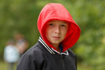 a boy in a black hoodie with a red hood,shot on a cloudy summer day