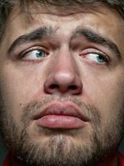 Close up portrait of young and emotional caucasian man. Highly detail photoshot of male model with well-kept skin and bright facial expression. Concept of human emotions. Looks sad and upset.