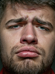 Fototapeta premium Close up portrait of young and emotional caucasian man. Highly detail photoshot of male model with well-kept skin and bright facial expression. Concept of human emotions. Looks sad and upset.
