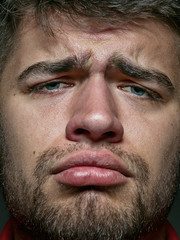 Close up portrait of young and emotional caucasian man. Highly detail photoshot of male model with well-kept skin and bright facial expression. Concept of human emotions. Looks sad and upset.