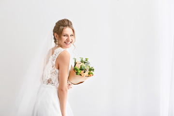 Beautiful young bride with bouquet of flowers on white background