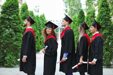 Happy students in bachelor robes outdoors