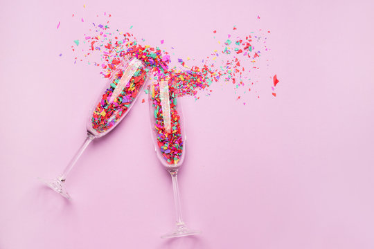 Glasses with confetti on color background