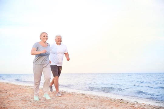 Sporty Mature Couple Running On Sea Beach