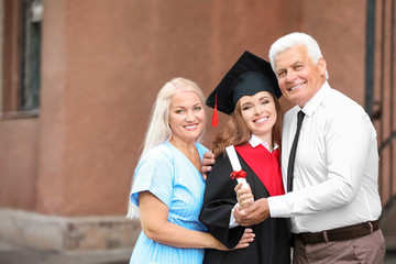 Happy young woman with her parents on graduation day