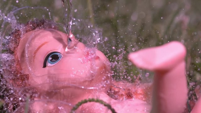 Pouring water on burnt baby dolls face slow motion