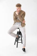 Fototapeta na wymiar Stylish young man sitting on stool against white background