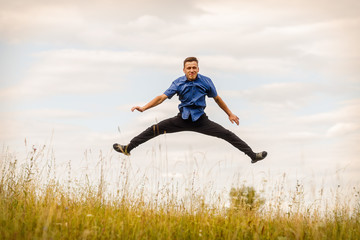 the jumping guy in the blue shirt outdoors on a summer day