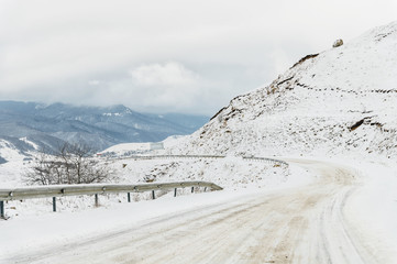 Empty mountain asphalt road in winter covered with snow on a cloudy day. The concept of driving a...