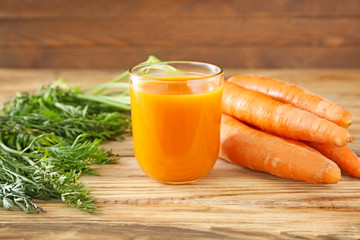 Glass of tasty carrot juice on wooden table