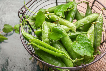 Basket with tasty fresh peas on color background, closeup