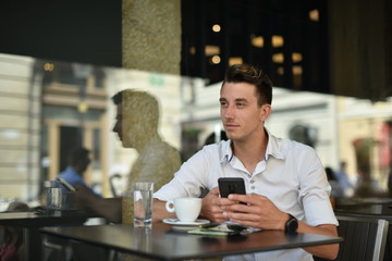 Young fashion man / hipster drinking espresso coffee in the city cafe during lunch time and working on tablet computer