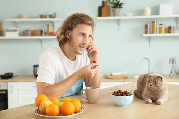 Man talking by phone while sitting at kitchen table with cute funny cat