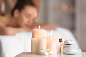 Beautiful burning candles with stones and essential oil on table in spa salon - obrazy, fototapety, plakaty