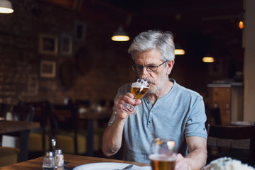 Senior man having a beer in the bar