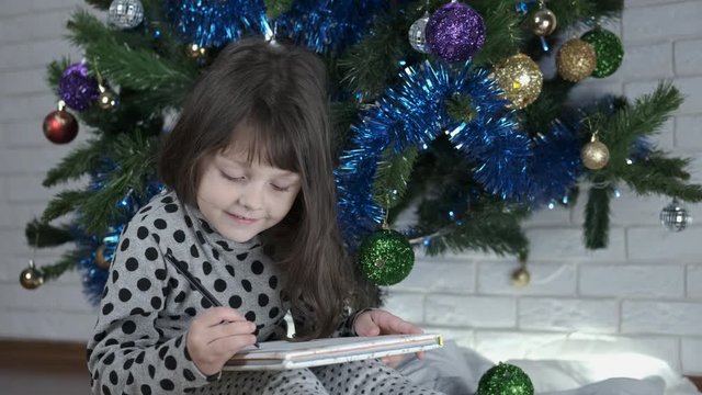 Painting for Santa. Cute little girl writes Christmas letters.