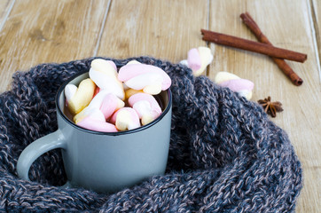 Cup of hot cocoa with marshmallows, woolen warm scarf, cozy winter evening