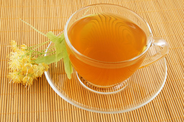 Cup of linden tea with lime tree blossoms on bamboo background