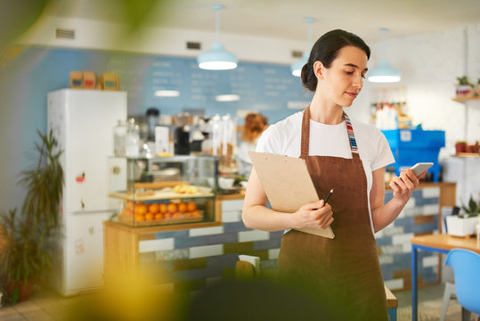 Barista standing while writing in the notepad.