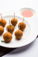 Crispy Veg lollipop recipe made using boiled potato with spices covered with corn flour and bread crumbs coating and then deep fried, served with toothpick or ice cream stock inserted in it with sauce
