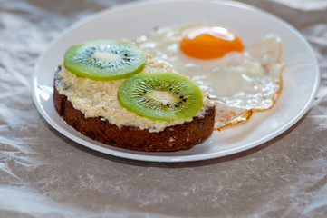 Delicious and healthy breakfast. Scrambled eggs and kiwi sandwich on a white plate, close-up, top view and side view