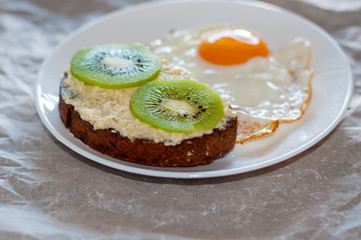 Obraz na płótnie Canvas Delicious and healthy breakfast. Scrambled eggs and kiwi sandwich on a white plate, close-up, top view and side view
