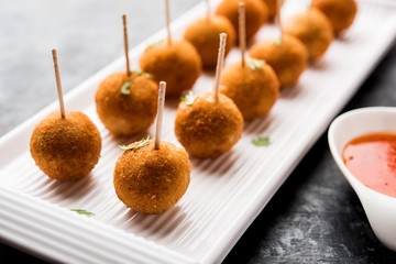 Crispy Veg lollipop recipe made using boiled potato with spices covered with corn flour and bread crumbs coating and then deep fried, served with toothpick or ice cream stock inserted in it with sauce