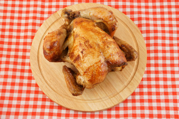 Roasted chicken on cutting board on tablecloth