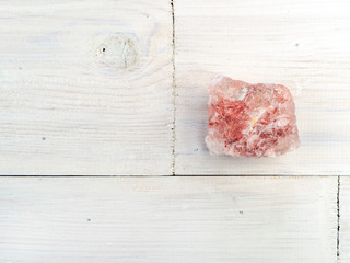 A large piece of Himalayan pink salt rock on a white wooden background. The concept of a basic salty taste, background with copy space