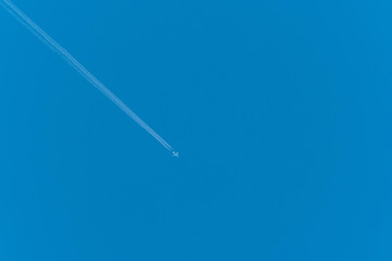 Jet airliner flying high in the sky leaves contrails in the clear blue sky 
