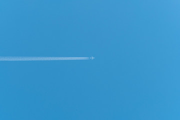 Jet airliner flying high in the sky leaves contrails in the clear blue sky 